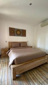 a bedroom with a large bed with a wooden frame at Cantika Guest House in Uluwatu
