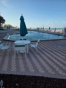 a table with an umbrella and chairs next to a pool at The Surf Shack at Harbour Beach Resort in Daytona Beach