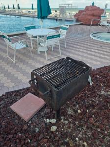 a barbecue grill with chairs and a table with an umbrella at The Surf Shack at Harbour Beach Resort in Daytona Beach +8 photos