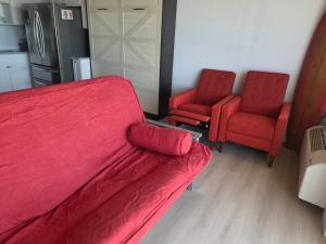 a bedroom with a bed and two red chairs at The Surf Shack at Harbour Beach Resort in Daytona Beach
