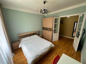 a bedroom with a large white bed and a chandelier at Russian Embassy Apartment in Ulaanbaatar