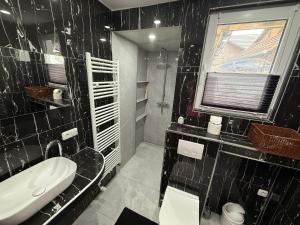 a black tiled bathroom with a sink and a toilet at Altstadtnest mit großem Garten in Bad Sooden-Allendorf +24 photos