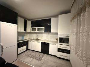 a kitchen with white cabinets and black and white appliances at Villa Calypso Sarajevo in Sarajevo