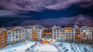 a hotel in the snow with mountains in the background at New Gudauri Twins Horizon in Gudauri