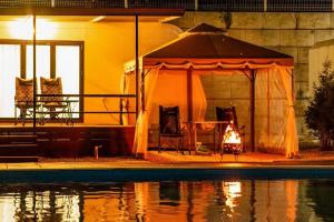 a gazebo with a fireplace next to a pool at night at The Cliff Caravan Camping in Pocheon