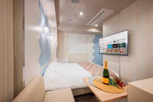a small bedroom with a bed and a bottle of wine at HOTEL Karin in Tokyo