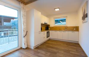eine Küche mit weißen Schränken und einem großen Fenster in der Unterkunft Ferienhaus Alpenherz in Finkenberg