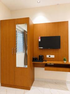 a room with a flat screen tv and a cabinet at K V Comforts in Chikmagalūr