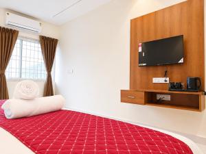 a hotel room with a red carpeted bed and a flat screen tv at K V Comforts in Chikmagalūr