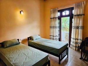 two beds in a room with a window at Deke Kanuwa in Kandy