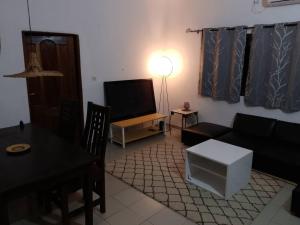 a living room with a couch and a table and a television at Le perchoir bleu in Lomé
