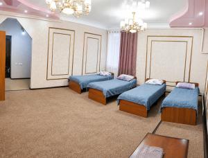 a room with four beds and a chandelier at Гостевой дом RICH in Bosteri