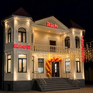 a white building with a kaze sign on it at Гостевой дом RICH in Bosteri
