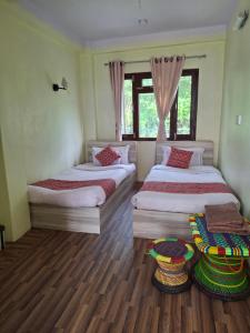 two beds in a room with wooden floors at Mountain View Homestay in Tānsen +7 photos