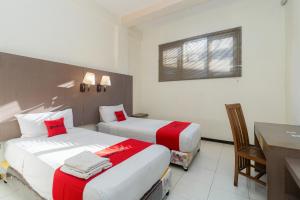 a hotel room with two beds and a desk at RedDoorz near Gubeng Station Surabaya in Bagongpatar