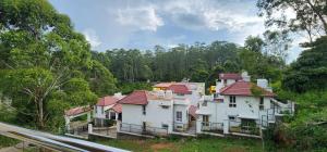 a large white house with red roofs on a hill at Grandwood Coco Resort Yercaud in Yercaud