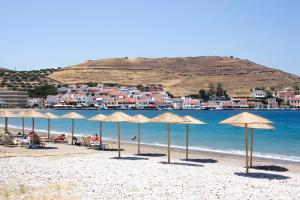 a beach with umbrellas and the water and buildings at Kea Harbor 2 in Korissia