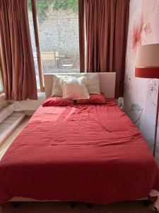 a red bed in a room with a window at Tastefully-decorated bedroom with garden access in Brussels