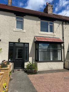 a house with a black door and a window at Bromielaw Room Only Accommodation in Seahouses