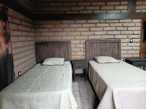 two beds in a room with a brick wall at Cabaña El Fresno in La Petaca