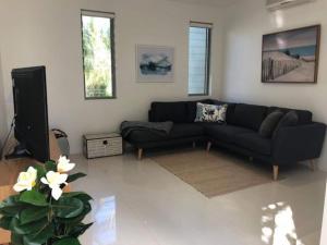 a living room with a black couch and a tv at Coastal Chic with Heated Pool Quiet Location in Sunshine Beach