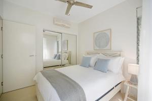 a white bedroom with a white bed and a mirror at Coastal Chic with Heated Pool Quiet Location in Sunshine Beach
