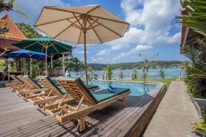a row of chairs and an umbrella next to a pool at The Old Island Huts in Nusa Lembongan