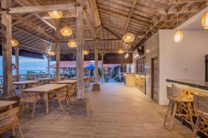 a restaurant with wooden ceilings and tables and chairs at The Old Island Huts in Nusa Lembongan