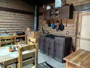 a kitchen with a stove and a table and a brick wall at Cabaña El Fresno in La Petaca