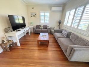 a living room with a couch and a flat screen tv at Our Place in South West Rocks