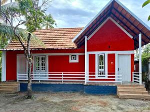 a red house with a red roof at Heinrich Wolfi Private Cotege in Pattiyūrgrāmam