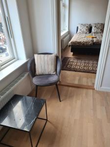 a room with a chair and a bed and a glass table at Hotel Damm in Aalborg +8 photos
