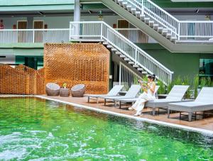 a woman sitting on a bench next to a swimming pool at Cross Vibe Chiang Mai Decem, Nimman in Chiang Mai
