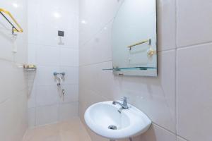 a white bathroom with a sink and a mirror at Urbanview Hotel Sany Cirebon in Tangkil