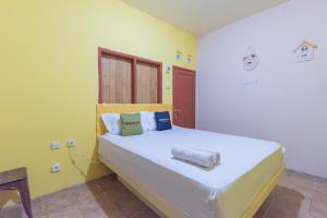 a bedroom with a large white bed with yellow walls at Urbanview Hotel Sany Cirebon in Tangkil