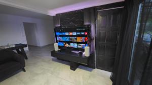 a living room with a flat screen tv next to a door at Entre Mer et Volcan ,piscine chauffée au tampon in Bel Air
