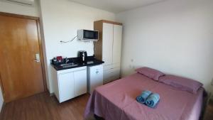 a bedroom with a bed with two blue shoes on it at Lagoa Flats com Super Varanda in Lagoa Santa