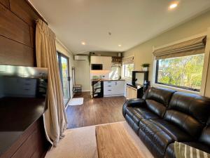 a living room with a leather couch and a kitchen at Modern Mountain Retreat in Ohakune