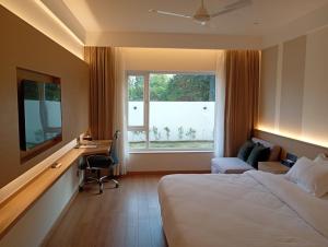 a hotel room with a bed and a desk and a window at Metta Shaanti Hotel Shravasti in Khargupur