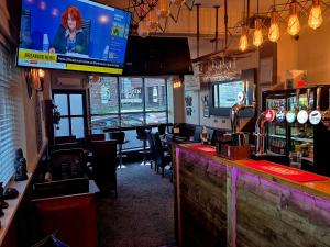 a bar with a large television and a bar with chairs at Miners Lamp Apartment in Easington
