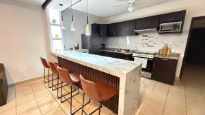 a kitchen with a counter and some brown chairs at Casa Ari in Lázaro Cárdenas