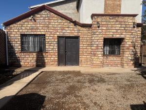 a brick house with a black door and two windows at Casa Ari in Lázaro Cárdenas