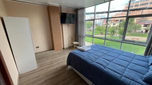 a bedroom with a blue bed and a large window at El Refugio del Rey in Cajamarca