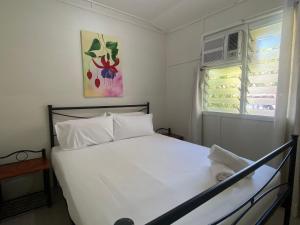 a white bed in a room with a window at The Barracks Arcadia 1 in Arcadia