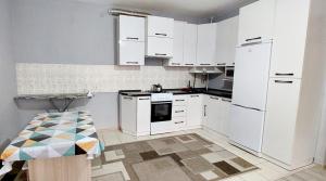 a white kitchen with white appliances and a table at ЖК Куралай in Qyzylorda