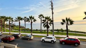 a group of cars parked in a parking lot with palm trees at Hotel Sunset Mar in Lima