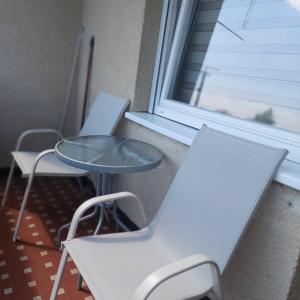 two white chairs and a table and a window at Dodi Apartman in Vonyarcvashegy