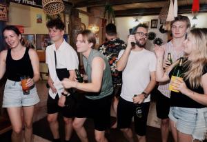 a group of people standing in a room with bottles of wine at The Cabin Backpackers Hostel & Bar in Chiang Mai