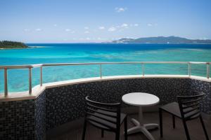 a balcony with a table and chairs and the ocean at Courtyard by Marriott Okinawa Resort in Nago
