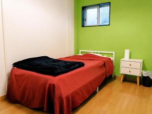 a bedroom with a bed with a red blanket at Guesthouse LuLuLu 無料朝食&夕食ｶﾚｰ付き ﾛｰｿﾝ隣 街まで電車8分 in Kochi